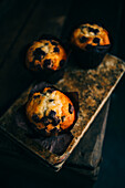 Chocolate muffins on an old book over a dark background