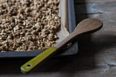 From above view of metal tray full of shelled walnuts with wooden spoon placed on table