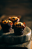 Delicious muffins with chocolate chips on dark wooden background