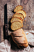 Von oben auf Scheiben von frisch gebackenem Vollkornbrot, die auf einem alten, schäbigen Holztisch in der Küche verstreut sind