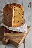 High angle of still life of sliced fresh baked artisan Christmas panettone cake on vintage book and cutting board against light background