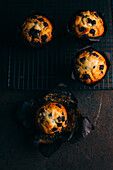 Chocolate muffins on cooling rack on dark background