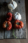 Reife rote Tomaten mit weißen Knoblauchzwiebeln auf einem Holztisch (von oben)