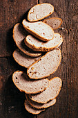 From above of slices of freshly baked wholegrain bread scattered on aged shabby wooden table in kitchen