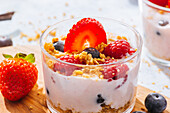 Close up of delicious homemade yogurt with strawberries, berries and cereals on white background