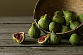 Closeup shot of basket with green figs and split fruit with red flesh on table