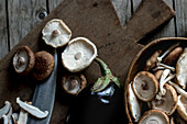 Blick von oben auf ein Holzbrett mit einer Schüssel voller Shiitake-Pilze und Auberginen darauf