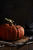 Whole ripe pumpkin with slightly ribbed skin placed on wooden table on placemat against black background
