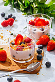 Von oben köstlicher hausgemachter Joghurt mit Erdbeeren, Beeren und Müsli auf weißem Hintergrund