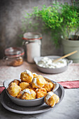 Bowl with crunchy nun's puffs bites stuffed with cream cheese placed on table in kitchen at home
