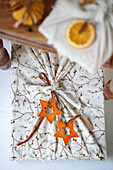 Gift in fabric packaging with dried orange slices and star pendants made of orange peel