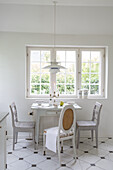 Small dining area with white country-style wooden furniture in front of the window