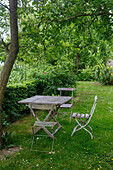 Garten mit rustikalen Holzmöbeln unter einem Baum im Sommer