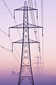 Electricity pylon in mist at dawn