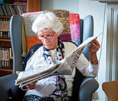 Care home resident reading a newspaper