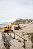 Mechanical digger reshaping coastal dunes