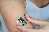 Person applying health monitoring sensor to arm