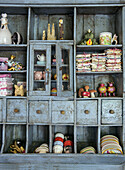 Vintage wooden shelf in blue with crockery and decorative figurines