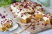 Carrot cake with cream cheese topping, nuts and pomegranate seeds
