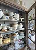 Porcelain cupboard with crockery, glasses and kitchen towels