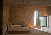 Schlafzimmer mit Steinwand und natürlicher Beleuchtung