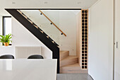 Modern kitchen with a view of the staircase, glass banister and integrated wine rack