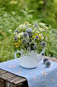 Colorful summer bouquet with globe thistles (Echinops) in an old teapot