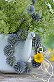 Wreath of thistles (Echinops) hanging from an old teapot