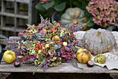 Colorful autumn wreath with hydrangeas (Hydrangea), heather, ornamental apples and rowan berries