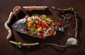 Halber roher und halber gegarter Fisch mit Tomaten, Tropea-Zwiebeln und Petersilie