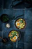 Gemüse-Porridge mit Avocadoscheiben und halbiertem Ei