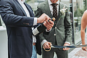 Man opens champagne bottle at an outdoor wedding reception