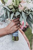 Braut mit Ehering und Hochzeitsstrauß aus rosa Rosen