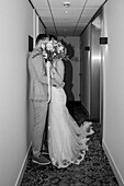 Wedding couple kissing in the hallway with a bouquet of flowers and elegant clothes