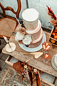 Three-tier, copper-colored wedding cake decorated with roses, wooden dresser with decoration