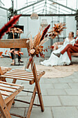 Autumnal decoration with dried flowers in a greenhouse, bridal couple in the background