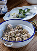 Dried flower buds and leaves in bowls on wooden table