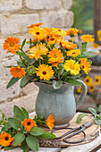 Bouquet of marigolds (Calendual) and sage leaves in a clay jug