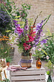 Bunter Strauß aus Gladiolen(Gladiolus), Herbstanemonen (Anemone Hupehensis) und Fenchelblüten auf Holzkiste