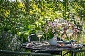 Sitzplatz im Garten mit gedecktem Tisch und Blumenstrauß aus Ballhortensie 'Annabell', Patagonisches Eisenkraut und  Herbstanemonen  (Anemone hupehensis)