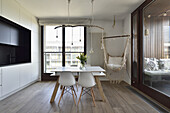 Moderne Wohnküche mit weißem Tisch, Stühlen, DIY-Hängeleuchte und Hängesessel