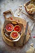 Sliced blood oranges in a basket on a wooden board