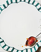 Löffel mit Tomatensauce auf gemustertem Teller