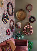 Living room wall decorated for Christmas with wreaths and mirrors