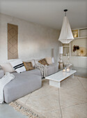 Boho-style living room with grey sofa, beige carpet and white hanging lamp