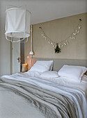 Bedroom with minimalist design, garland on the wall and large ceiling lamp