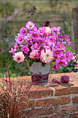 Strauss aus Dahlien (Dahlia) und Cosmea (Cosmos) auf Gartenmauer