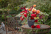 Herbstlicher Strauß aus Dahlien (Dahlia), Myrtenaster, Rosen, orientalischer Knöterich, Gartenfuchsschwanz (Amaranthus caudatus) auf Gartentisch