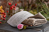 Note with handwritten poem about autumn, with linen napkin, rose blossom and rose hips, still life