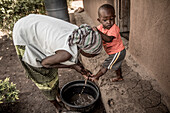 Mother washing her son's feet, Kenya